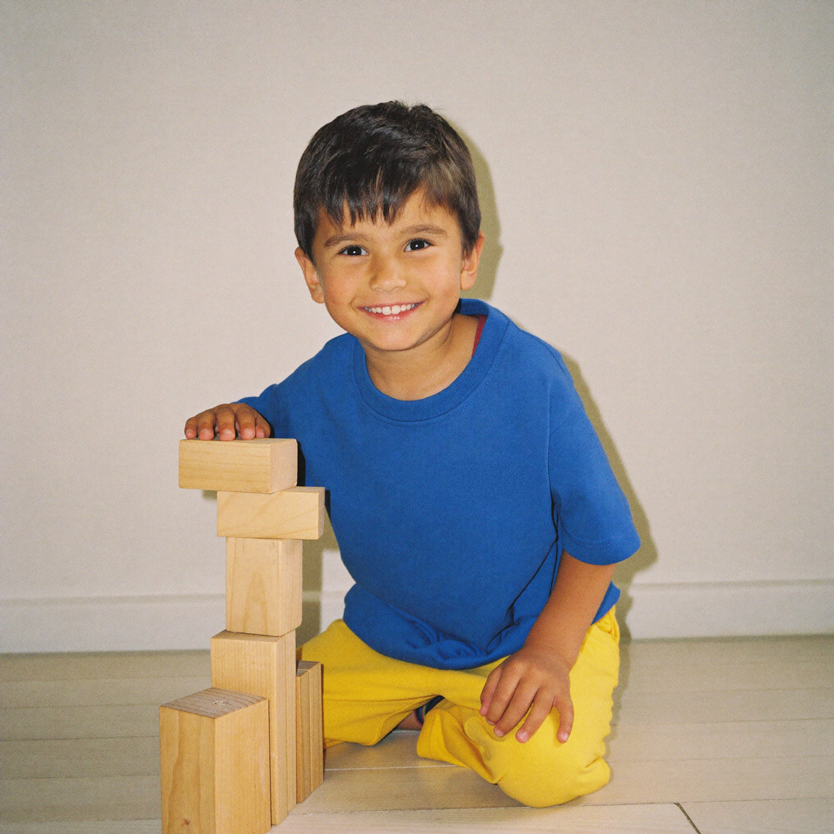 Lachende jongen bouwt een toren van houten blokken