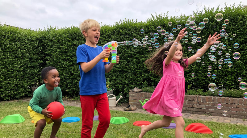 Drie kinderen spelen buiten in de tuin met bellenblaas